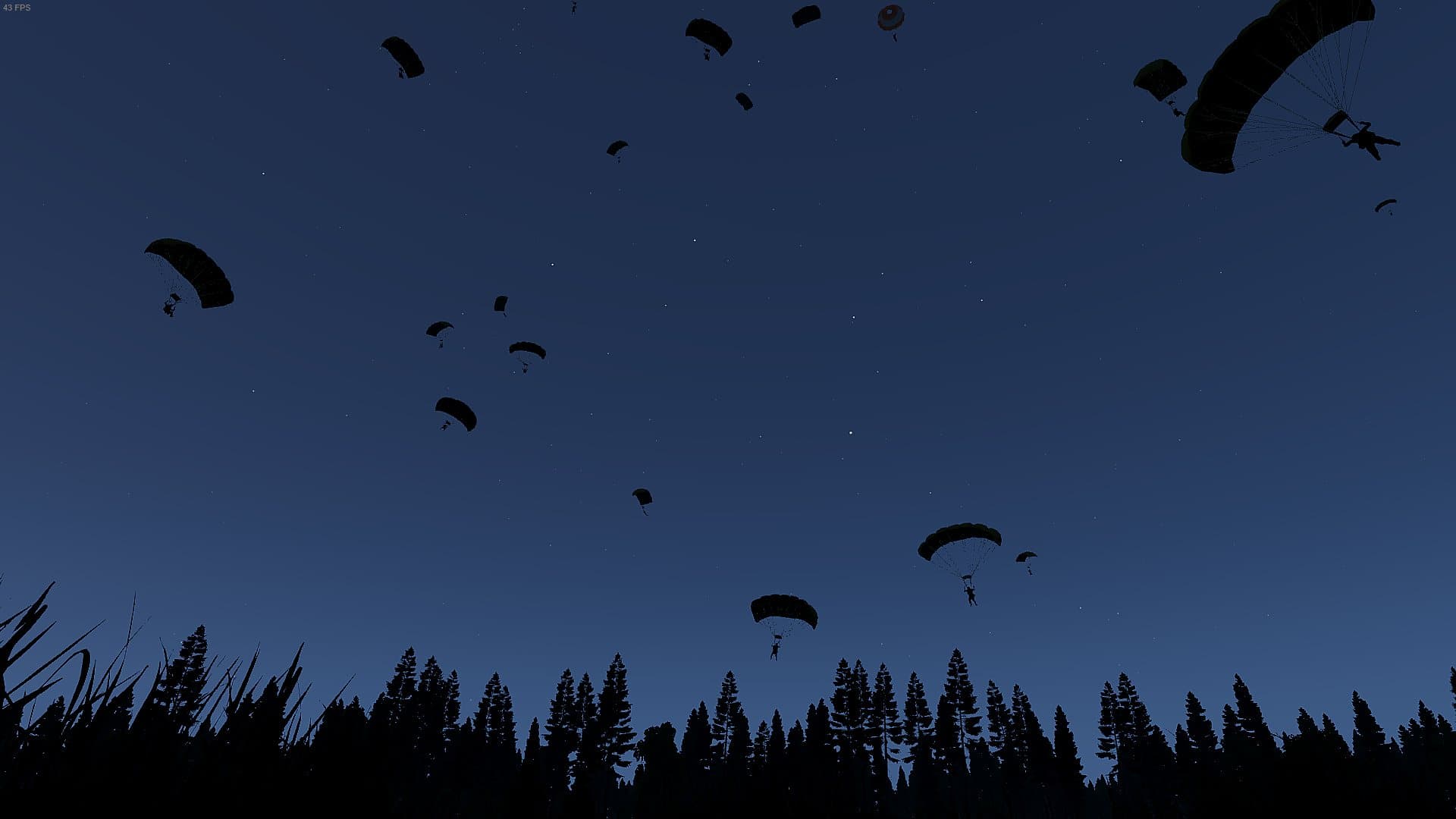 A mass night parachute drop silhouetted over the treeline